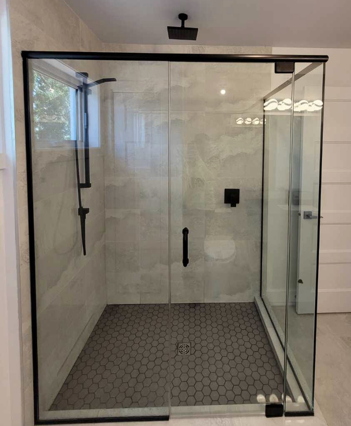 Douche vitrée avec porte coulissante et encadrement noir
