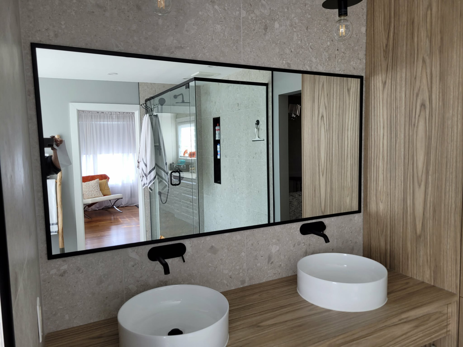 Grand miroir mural à cadre noir au-dessus d'une vanité double