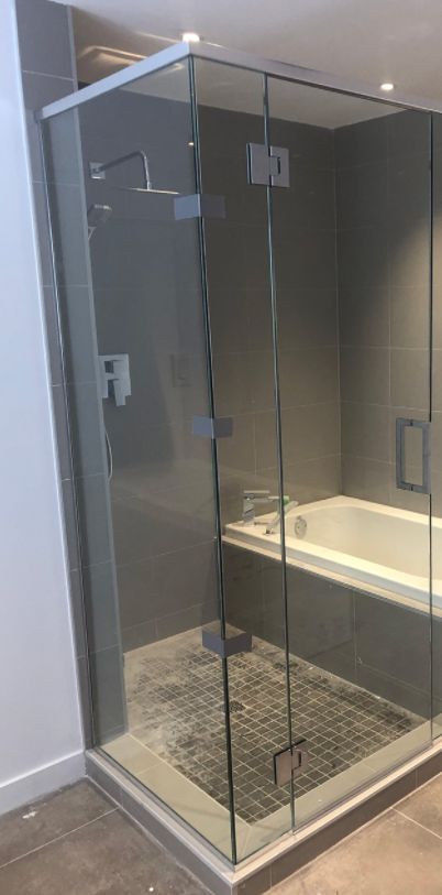Douche vitrée en coin avec porte sur pentures