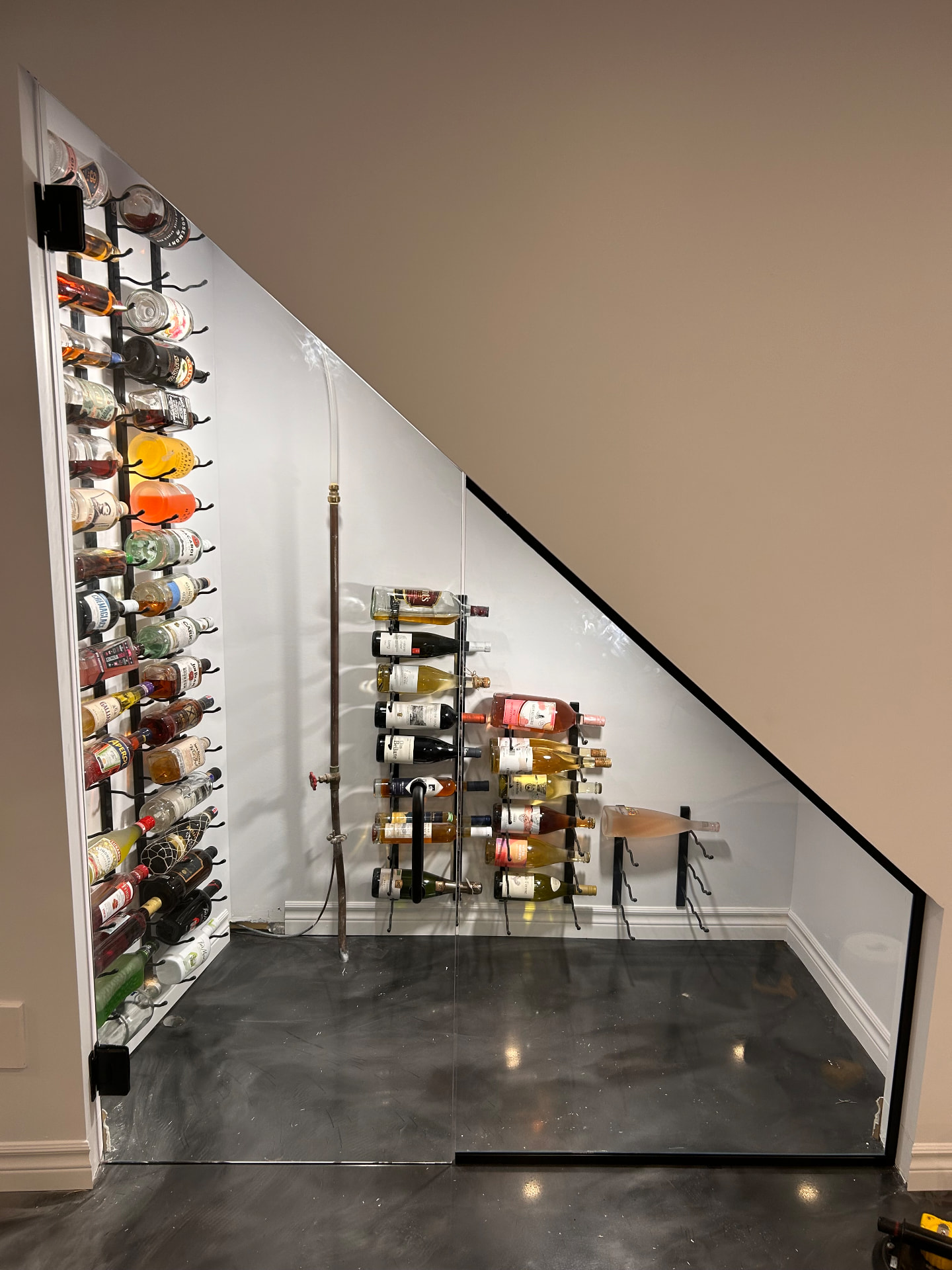 Cellier vitré aménagé sous un escalier avec porte en verre